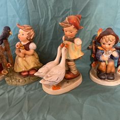 three figurines of children with birds on them