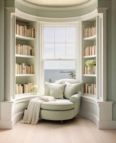 a white couch sitting under a window next to a bookshelf filled with lots of books