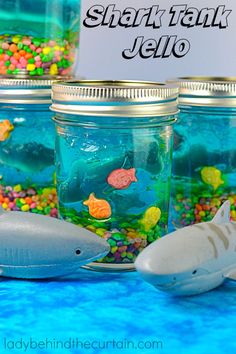 there are many fish in the jar on the table and one shark is next to it