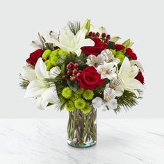 a vase filled with white and red flowers on top of a marble countertop in front of a white wall