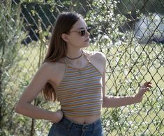 a woman standing next to a chain link fence