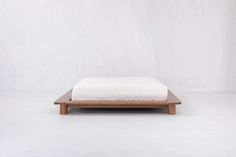 a bed sitting on top of a wooden platform in front of a white wall and floor