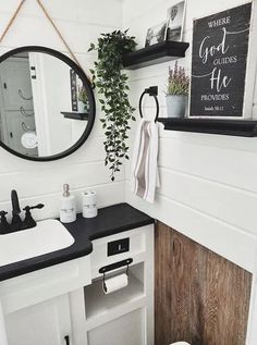 a white bathroom with black counter tops and wooden accents, along with a mirror above the sink