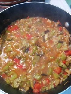 a pot filled with soup sitting on top of a stove next to a pan full of food