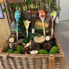 a basket filled with wooden spoons and fake animals sitting on top of green moss