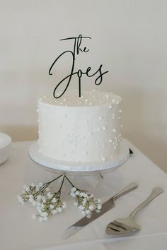 a white wedding cake with the word the jones on top and flowers next to it