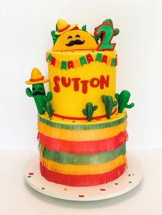 a yellow birthday cake with cactus decorations and the number two on it's top