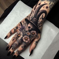 a woman's hand with flowers and a goat head tattoo on her left hand