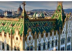 an ornate building with green and white paint on it's roof, in front of the city skyline