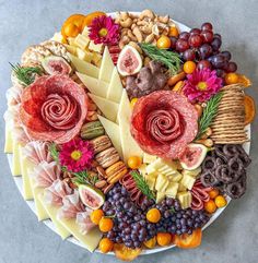 a platter filled with different types of cheeses, meats and fruit arranged on top of each other