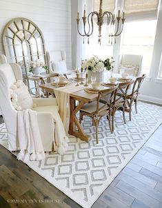 the dining room table is set with white chairs and place settings for four people to sit at