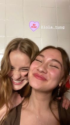 two young women are smiling while taking a selfie in the bathroom with their eyes closed