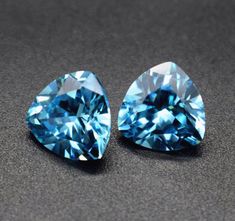 two blue diamonds sitting on top of a black table next to each other and one is in the shape of a heart