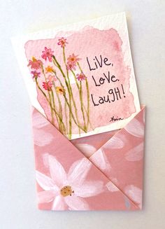 a pink envelope with some flowers on it and a card saying live, love, laugh