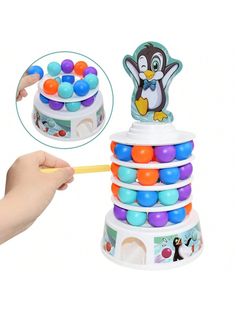 a child's hand is holding a toy penguin tower