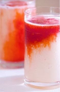 two glasses filled with liquid sitting on top of a white table next to each other