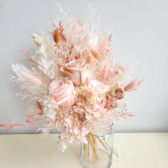 a vase filled with lots of pink flowers on top of a white table next to a wall