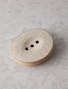 a white ceramic object with two holes in the middle on a marble surface, top view