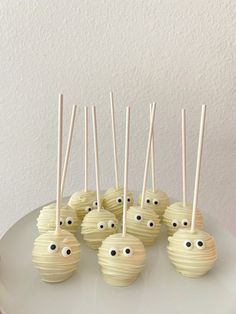 cake pops with googly eyes and sticks sticking out of them on a white plate