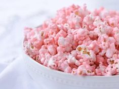 a bowl filled with pink and white popcorn on top of a table next to a napkin