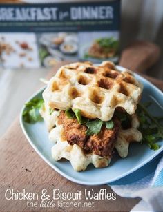 a chicken and waffle sandwich with lettuce on a blue plate sitting on a wooden table