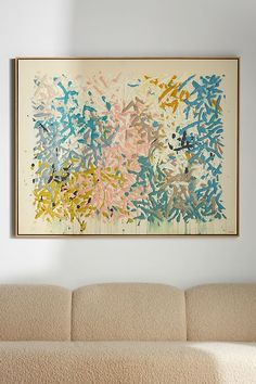 an abstract painting hangs on the wall above a couch