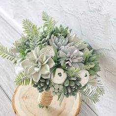 an arrangement of succulents and greenery in a wooden vase