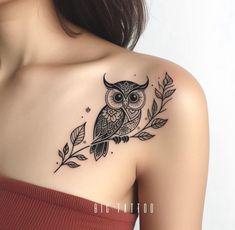 an owl tattoo on the back of a woman's shoulder and arm, with leaves