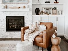 a living room filled with furniture and a fire place in front of a white brick wall