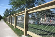 the fence is made of wood and has a chain link design on it, along with green grass