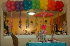 balloons and streamers are hanging from the ceiling above a table with a blue cloth on it