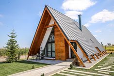 a house made out of wood and metal with a pitched roof on the grass area