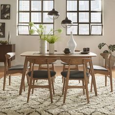 a dining room table with chairs and vases on it in front of large windows