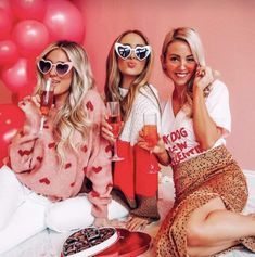 three beautiful women sitting next to each other holding drinks