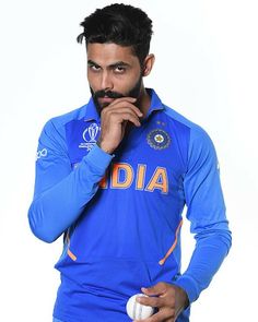 a man in blue jersey holding a ball and posing for the camera with his hand on his chin