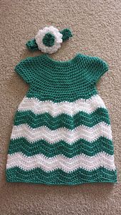 a crocheted green and white dress with a flower on it