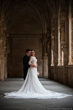 a bride and groom pose for a photo in an old building with stone arches on either side