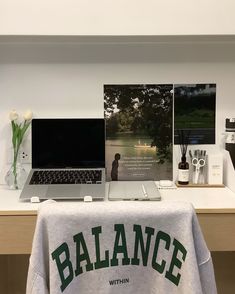 a laptop computer sitting on top of a desk next to a t - shirt that says balance