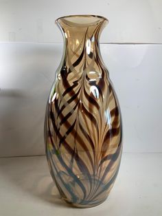 a large glass vase sitting on top of a white table next to a planter