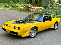 a yellow sports car parked on the side of a road in front of some trees