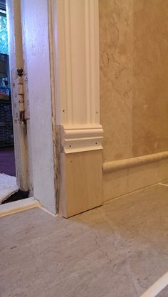 an open door leading to a bathroom with marble flooring and white trim on the walls