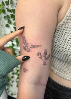 a woman's arm with two small birds on the left side of her arm