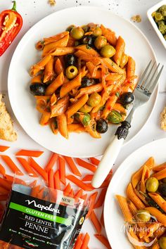 two plates of pasta with olives and bread on the side, next to a bag of penne