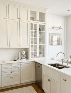 a kitchen with white cabinets and gold handles on the sink, dishwasher and oven