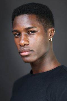 a young man in a black t - shirt is posing for a photo with his head tilted to the side