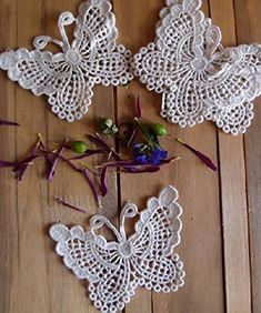 crocheted doily with flowers and butterflies on wooden floor next to each other