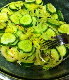 a bowl filled with sliced cucumbers and a fork on top of the bowl