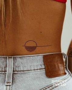 the back of a woman's stomach with a small circle tattoo on her left side