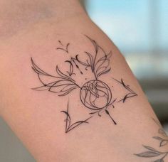 a woman's arm with a tattoo on it that has an arrow and leaves