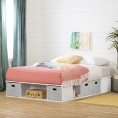 a bed with two storage drawers underneath it in a white room next to a window